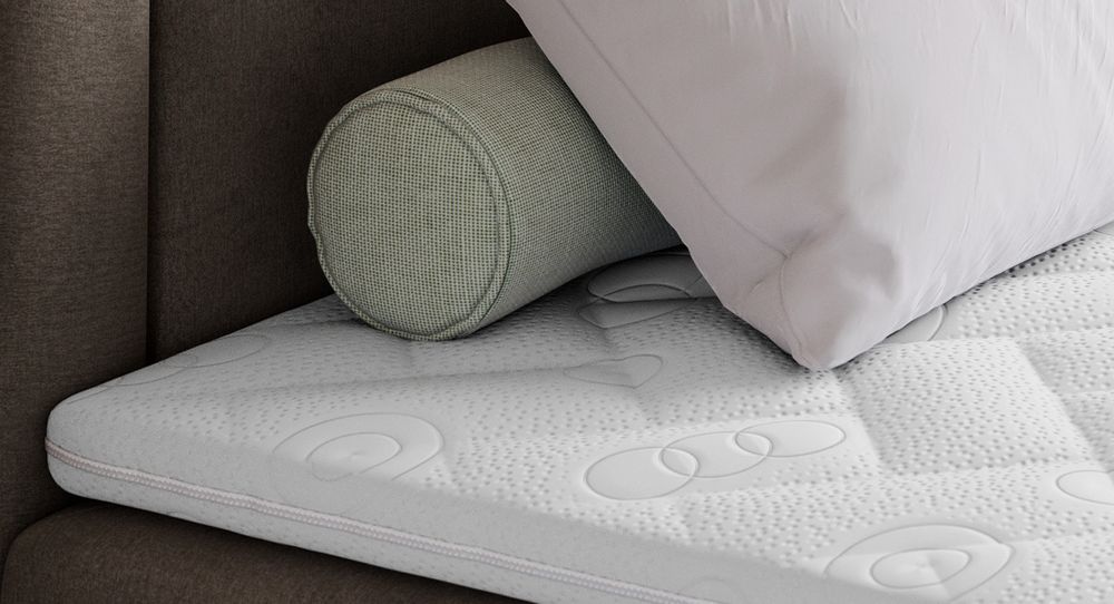 Gestepptes Kopfteil eines braun Bettes. Eine Topper-Matratze liegt auf dem Bett