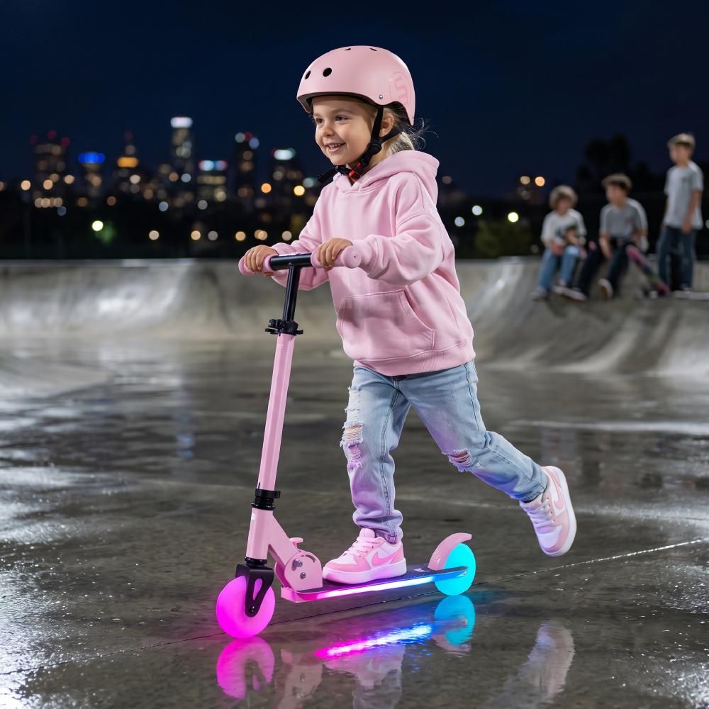 Kind fährt nachts mit beleuchtetem Tretroller im Skatepark