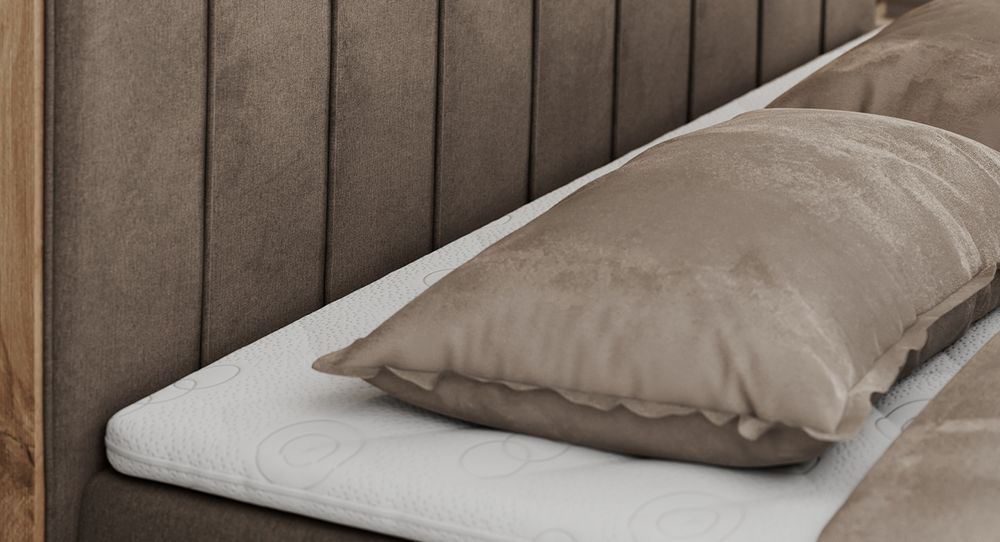Gestepptes Kopfteil eines braun Bettes. Eine Topper-Matratze liegt auf dem Bett