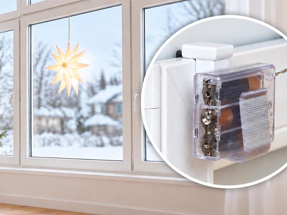Das Bild zeigt einen leuchten Weihnachtsstern, welcher mit Fensterhaken am Fenster befestigt ist.
