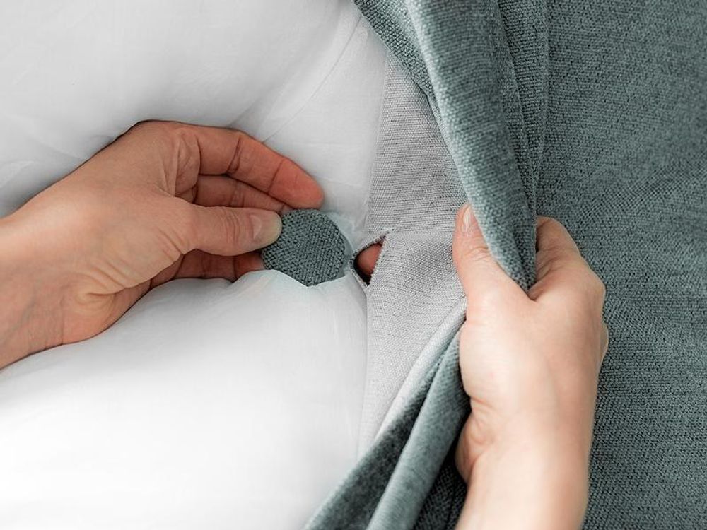 Detailansicht der Knopfheftung und der weißen Kissenfüllung.