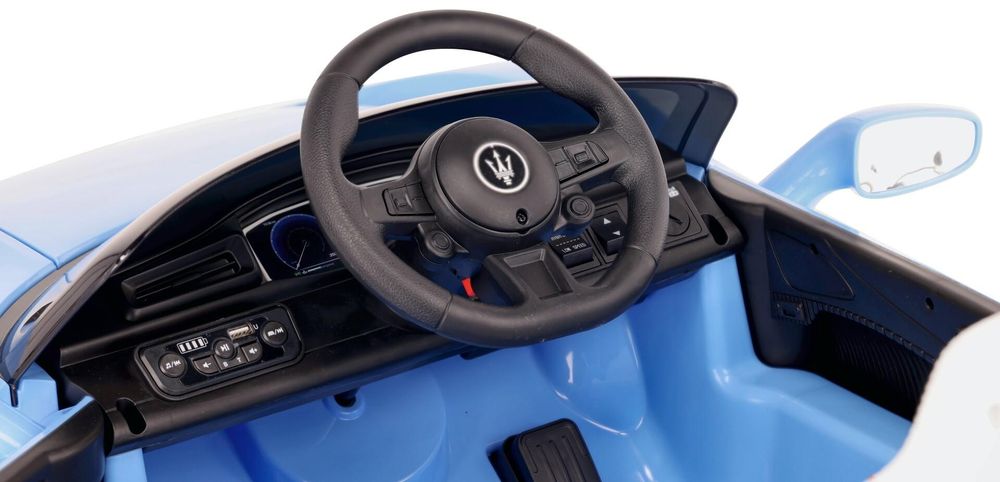 Primer plano del volante y panel multimedia del coche eléctrico infantil.