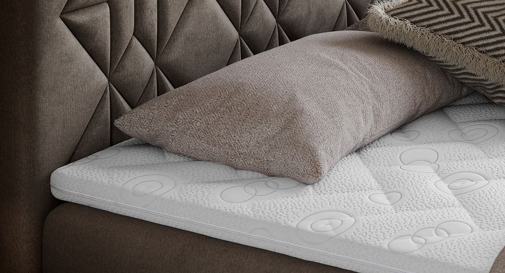 Gestepptes Kopfteil eines braun Bettes. Eine Topper-Matratze liegt auf dem Bett