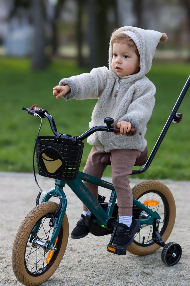 Niño pequeño sentado en la bicicleta, siendo guiado por un adulto.