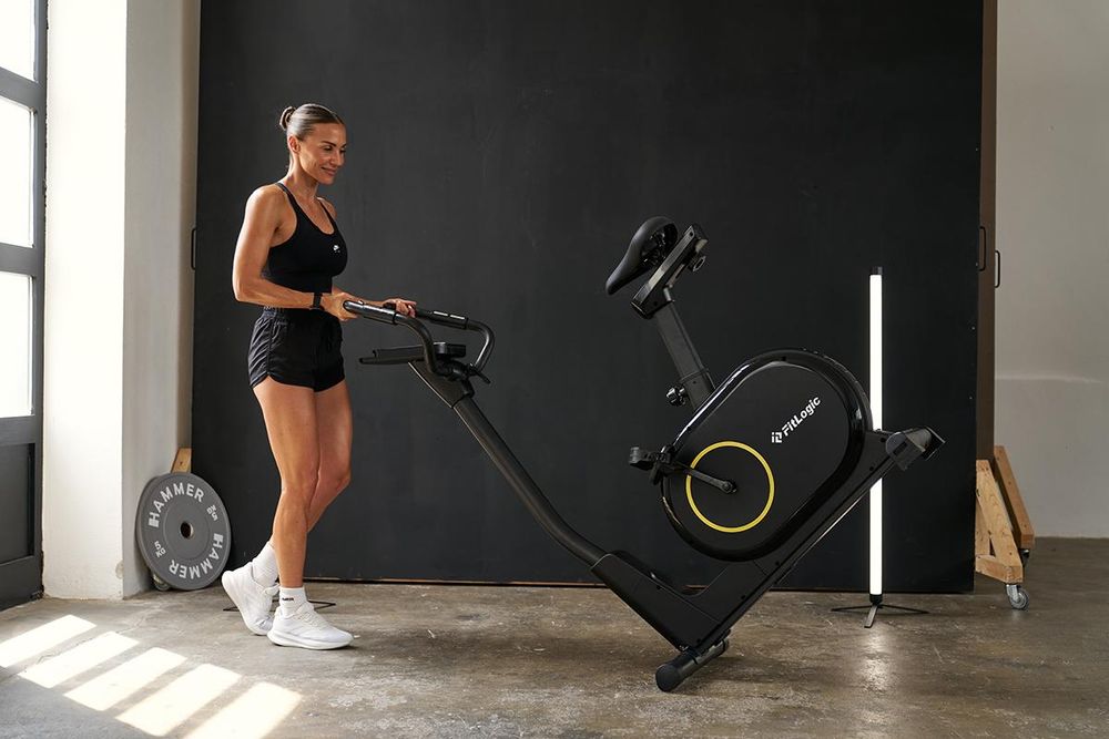 Das Bild zeigt eine Frau, die den FitLogic Cardio X2 auf den Transportrollen im Raum bewegt