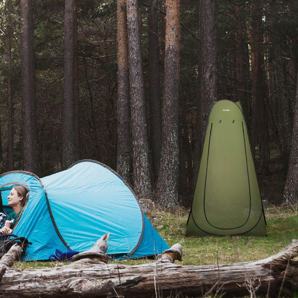 Frau in blauem Zelt. Grünes Pop-up Duschzelt/Toilettenzelt im Wald