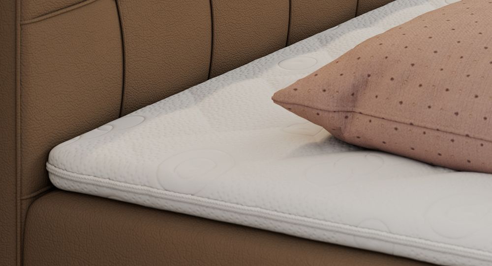 Gestepptes Kopfteil eines braun Bettes. Eine Topper-Matratze liegt auf dem Bett