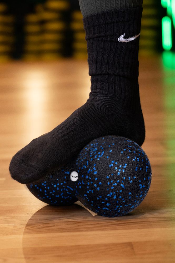 Osoba ćwicząca i wykorzystująca piłkę do masażu duoball FIZYO 24x12 cm