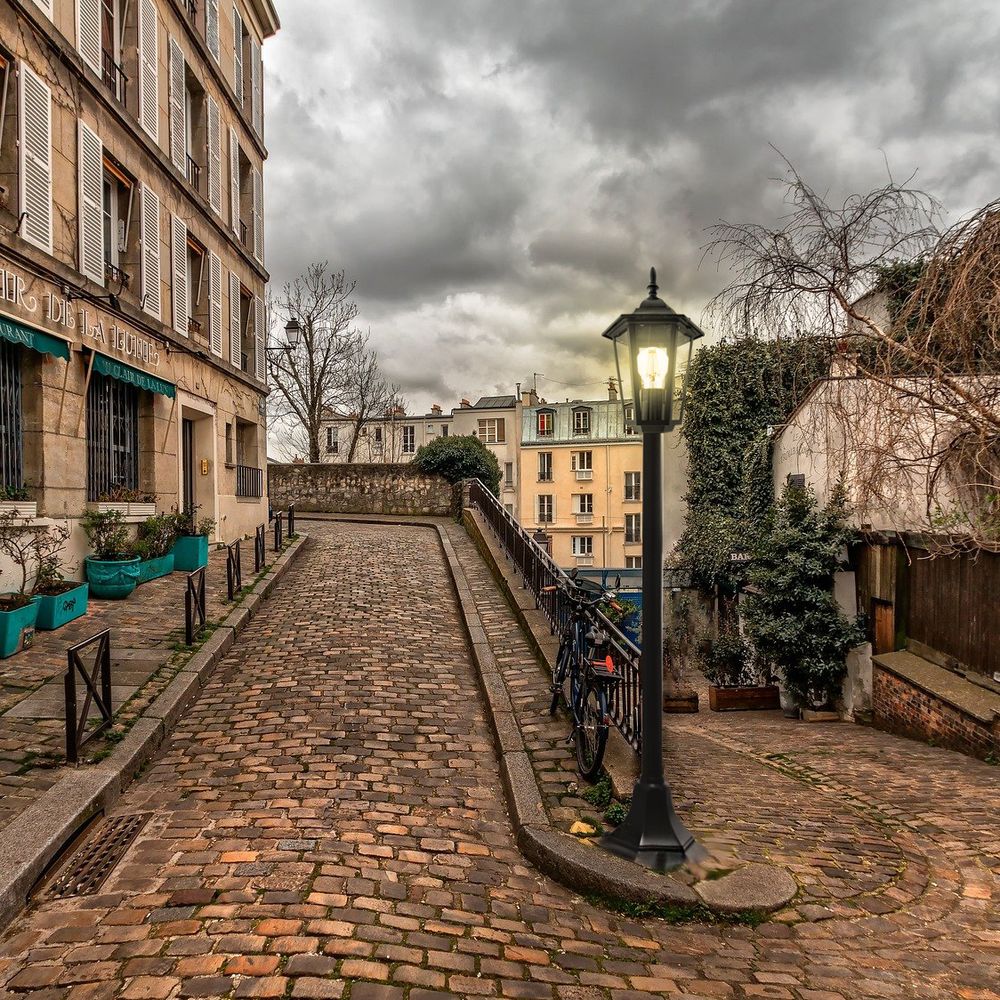 Pariser Gasse mit klassischem Design der Beleuchtung, Steinweg unter bewölktem Himmel.