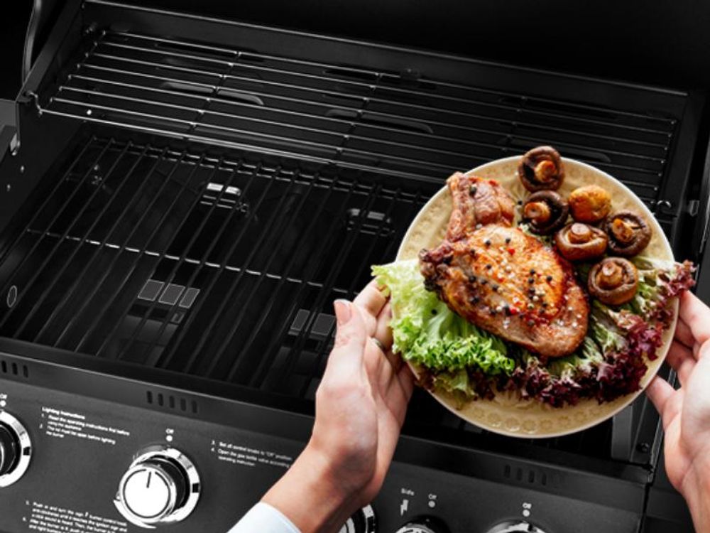 Teller mit gegrillter Hähnchenbrust und Champignons über der Grillfläche des TAINO BRANDO 4+1