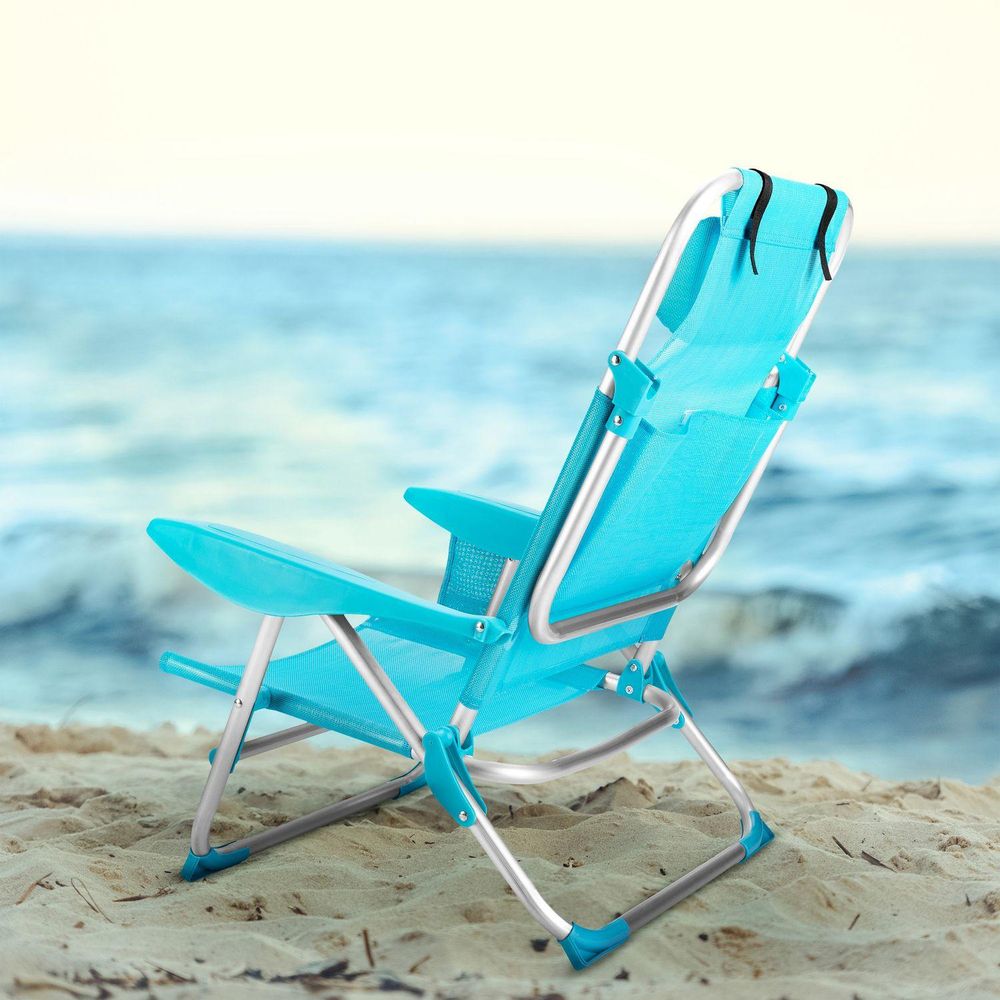 Blauer, klappbarer Strandliegestuhl auf Sand vor der Kulisse des Meeres