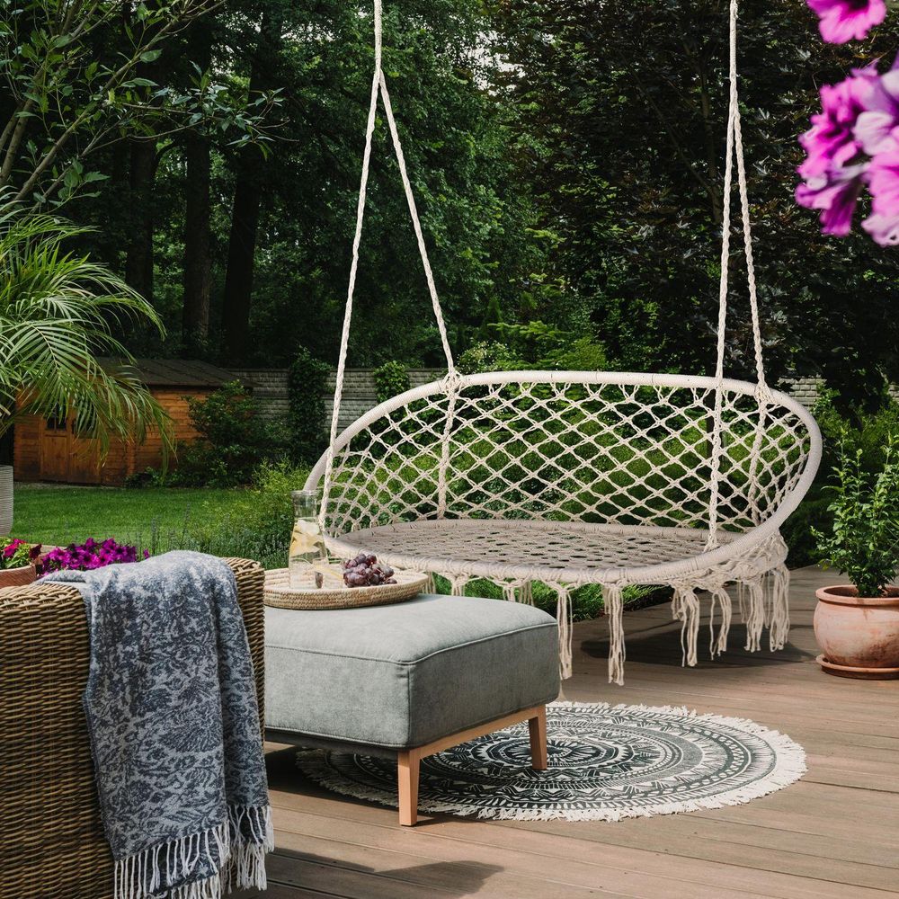 Schicker Makramee-Hängesessel auf einer Holzterrasse als Outdoor-Sitzgelegenheit