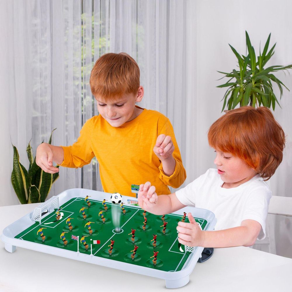 Zwei Jungen spielen begeistert eine Runde Tischfußball auf einem weißen Tisch