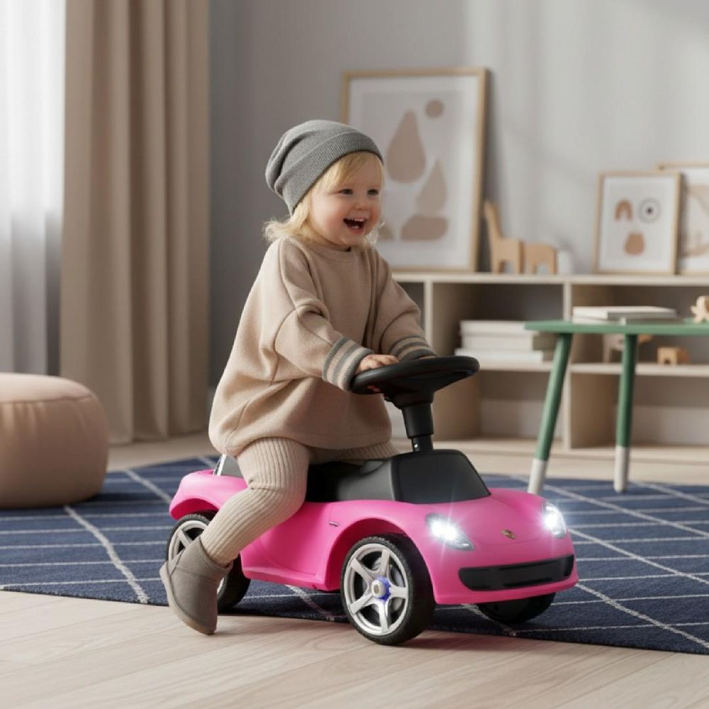 Kind fährt lachend auf dem Rutschauto im Wohnzimmer