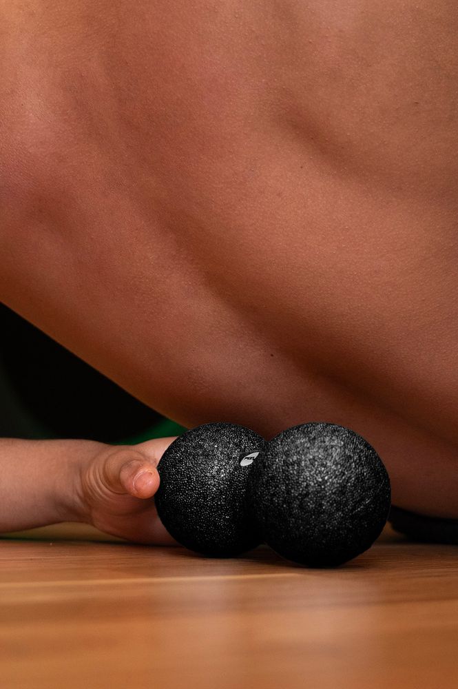 Osoba ćwicząca i wykorzystująca piłkę do masażu duoball FIZYO 16x8 cm