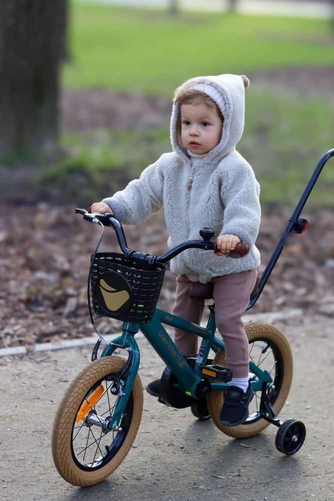 Niño montando la bicicleta con ruedines, sin la ayuda directa de un adulto.