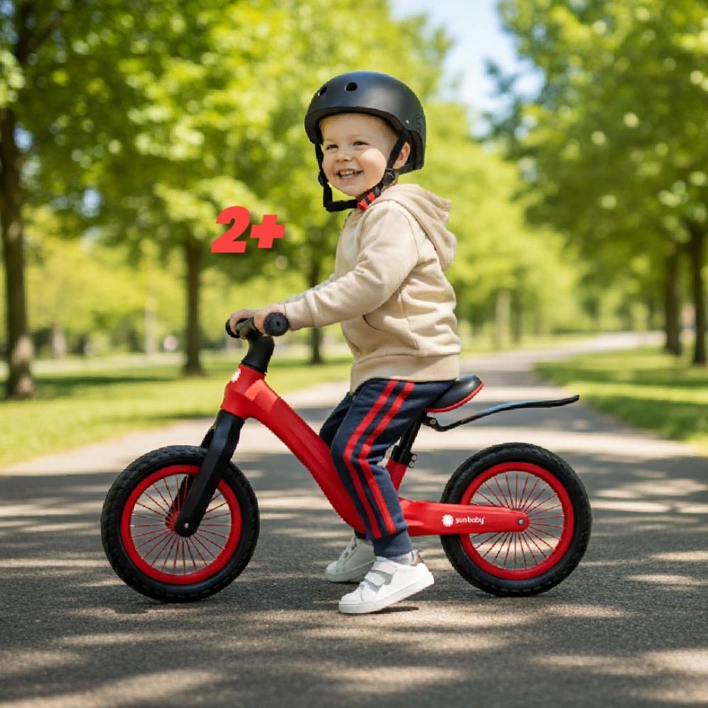 Dítě sedící na odrážedle Sun Baby Sport v parku, označení věku 2+.