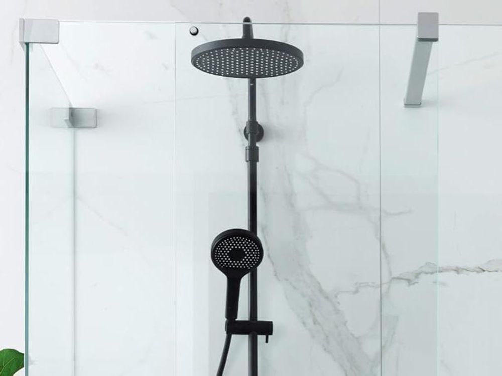 Modernes schwarzes Duschsystem BIELLA mit Kopfbrause und Handbrause vor heller Marmorwand.