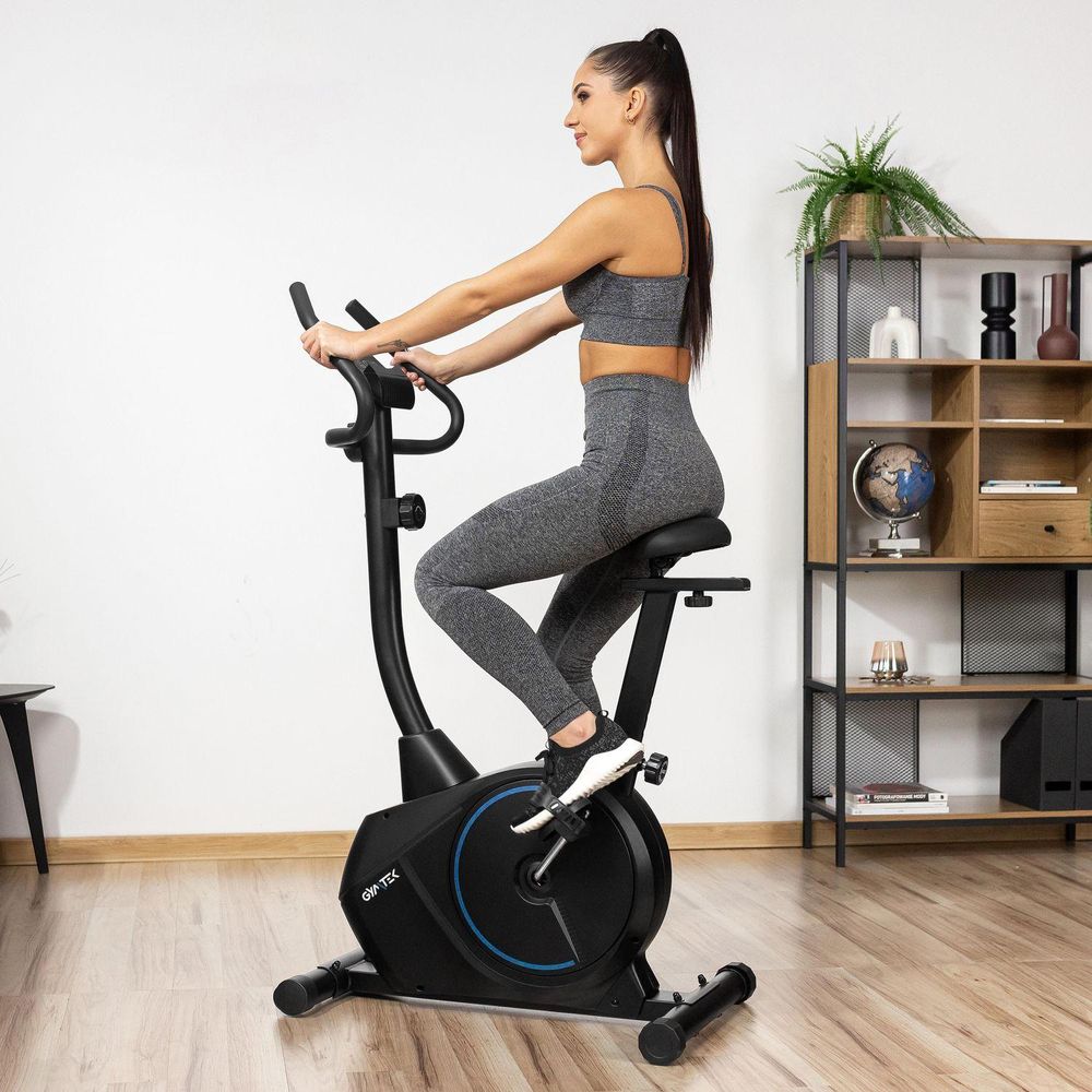 Seitenansicht einer jungen Frau, die im Wohnzimmer auf dem schwarzen Heimtrainer trainiert