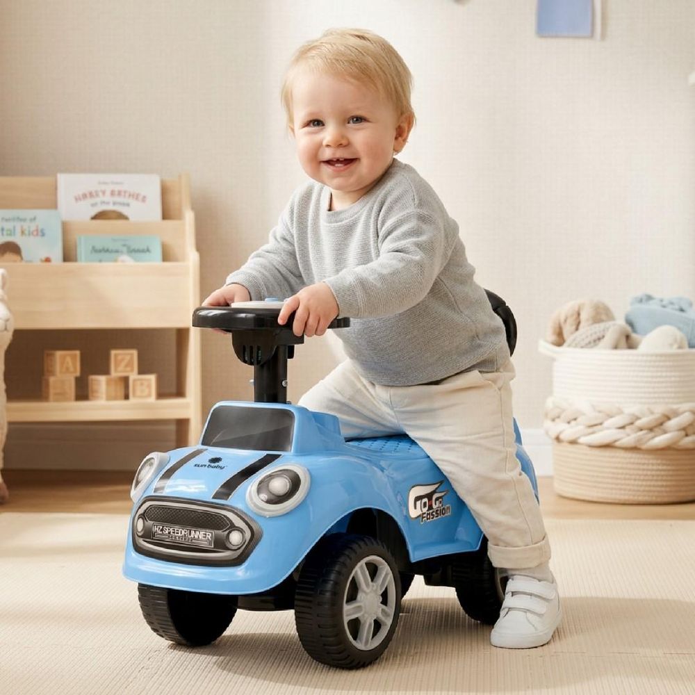 Kind sitzt auf blauem SUN BABY Rutschauto im Kinderzimmer