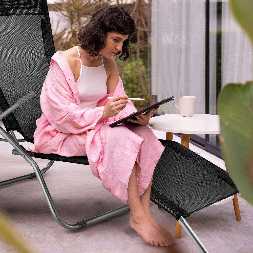 Frau sitzt auf Sonnenliege und arbeitet auf einem Tablet. Komfortables Home Office