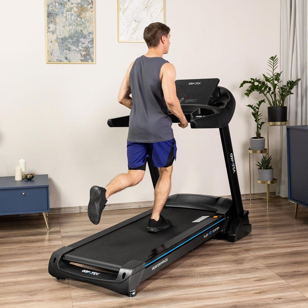 Mann joggt von hinten gesehen auf einem Laufband im modernen Wohnzimmer