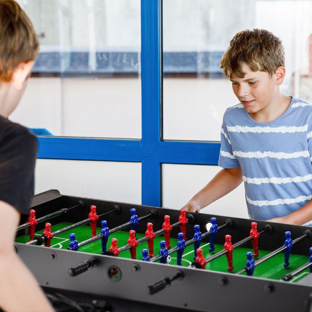 Junge Kinder spielen begeistert Tischfußball drinnen