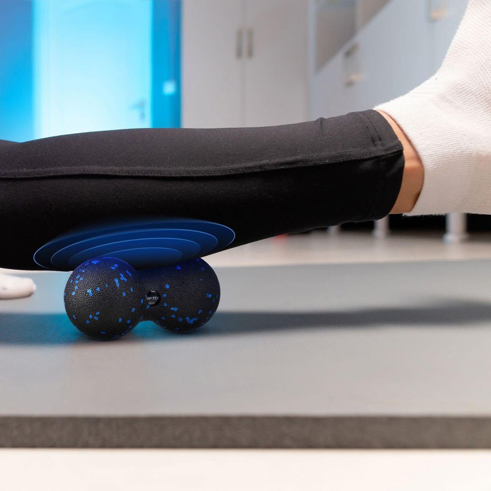 Nahaufnahme der Anwendung des Massage-Duoballs unter der Wade auf einer Matte