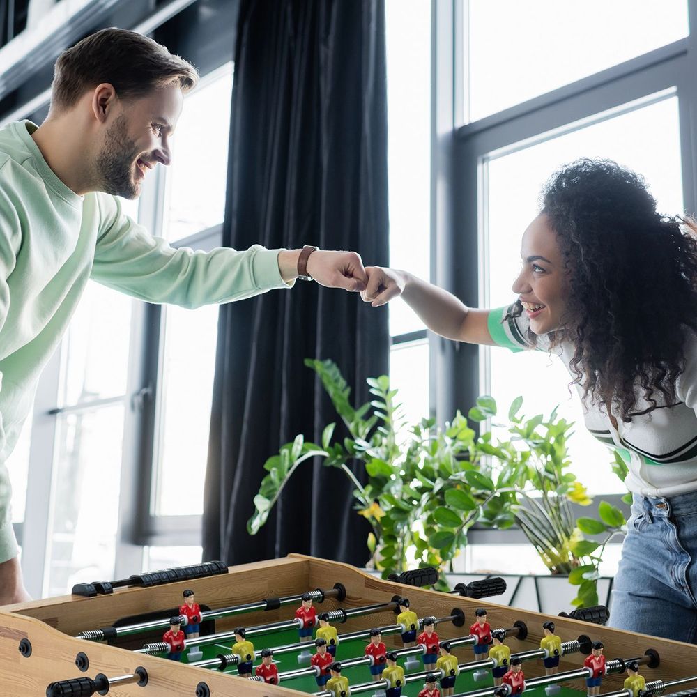 Freunde geben sich ein "Fist Bump" nach einem Tischfußballspiel.