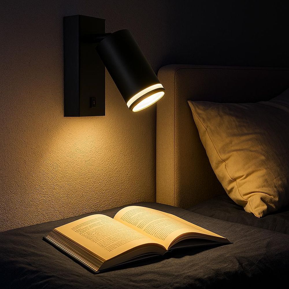 Schwarze LED-Wandleuchte mit Schalter über Bett, beleuchtet offenes Buch im warmen Licht.