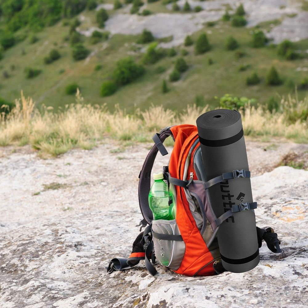 Gerollte Outtec Isomatte am orangefarbenen Rucksack befestigt. Bereit für Wanderungen