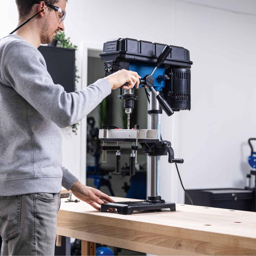 Das Bild zeigt eine Person bei der Arbeit mit der Tischbohrmaschine.