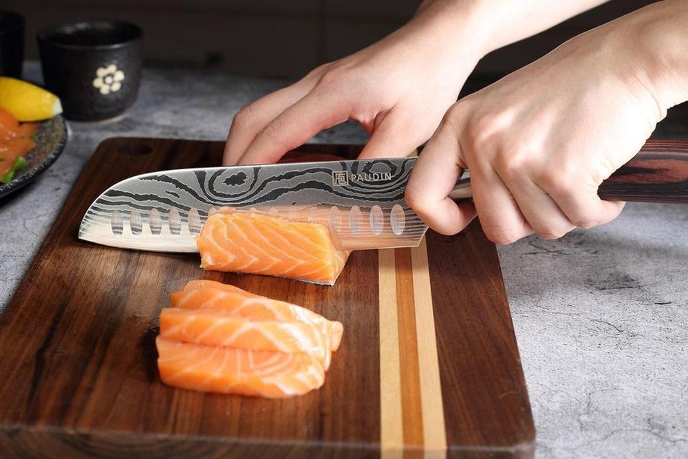 Santokumesser PAUDIN N5 beim Schneiden von Lachs auf einem Holzbrett