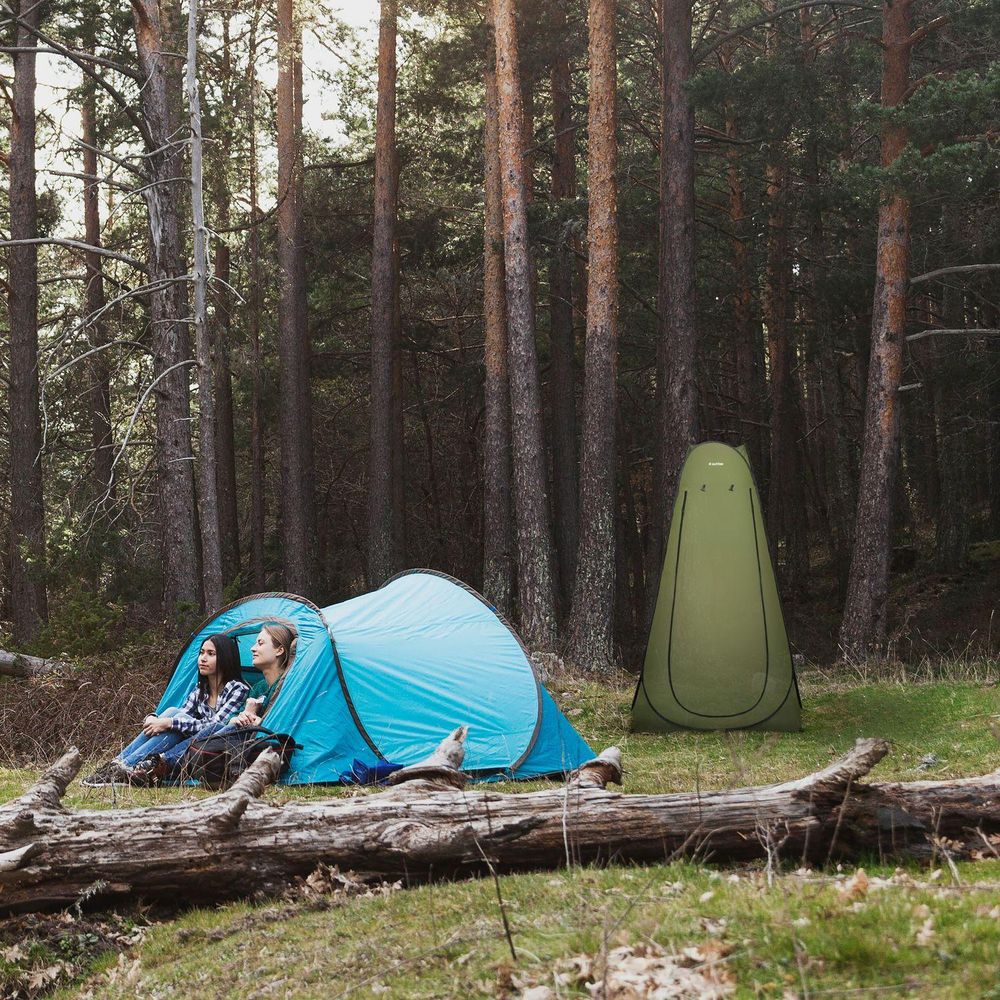 Zwei Frauen in blauem Zelt. Grünes Pop-up Duschzelt/Toilettenzelt im Wald