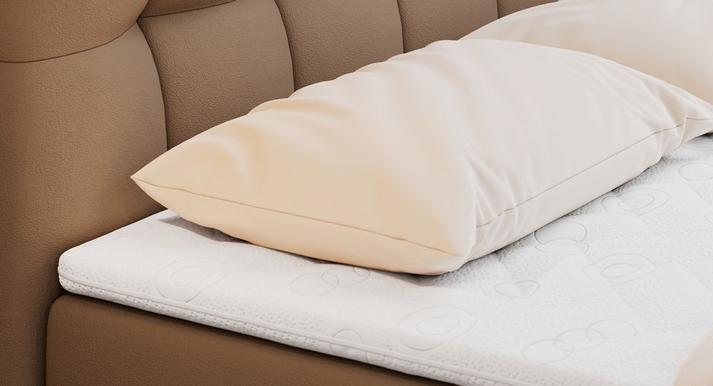 Gestepptes Kopfteil eines braun Bettes. Eine Topper-Matratze liegt auf dem Bett