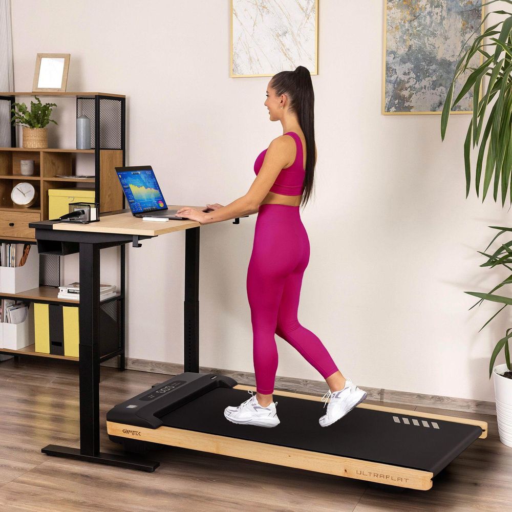Frau arbeitet am Stehschreibtisch und nutzt dabei das Walking Pad