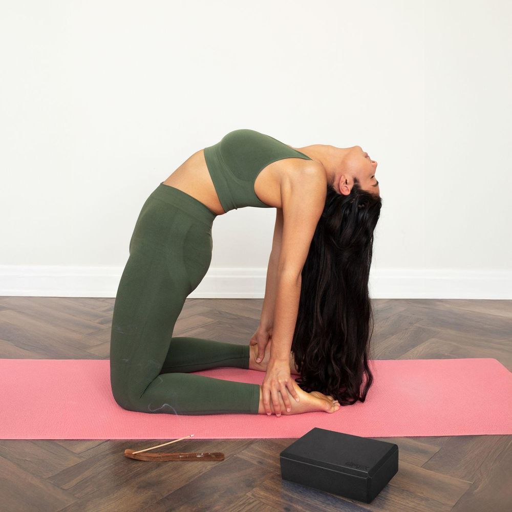 Frau macht Kamelhaltung auf Yogamatte mit Yogablock