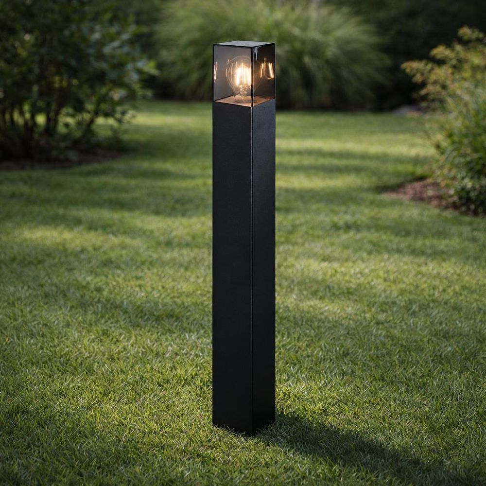 Hohe schwarze Außenleuchte mit klarem Glasaufsatz und sichtbarer LED-Filamentlampe für Gartenwege.