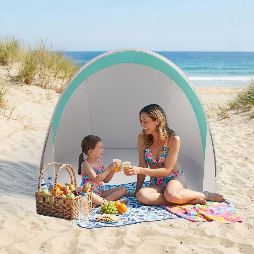 Mutter und Tochter machen Picknick im blau-grauen Strandzelt am Meer