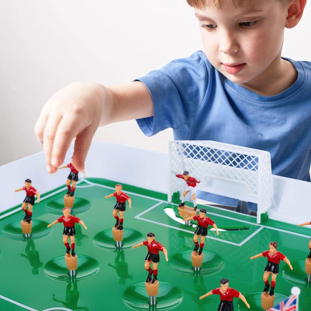 Ein Kind spielt Tischfußball und schießt ein Tor