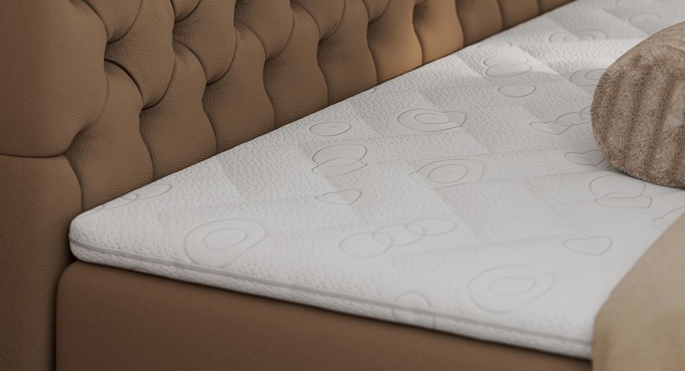 Gestepptes Kopfteil eines braun Bettes. Eine Topper-Matratze liegt auf dem Bett