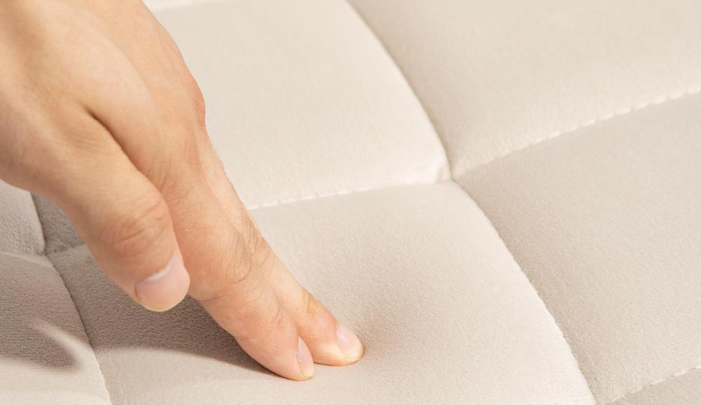 Hand drückt auf weiches Samtpolster mit Karomuster.