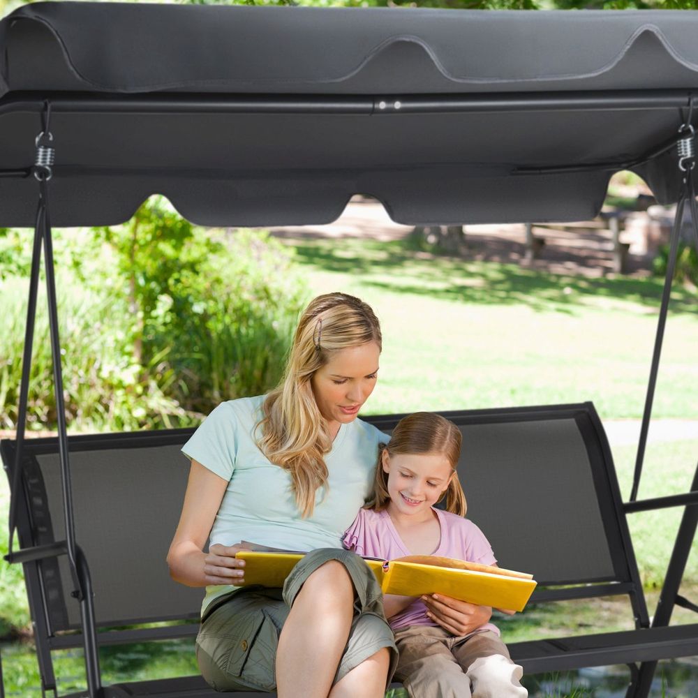 Mutter und Tochter lesen gemeinsam auf einer grauen Gartenschaukel.