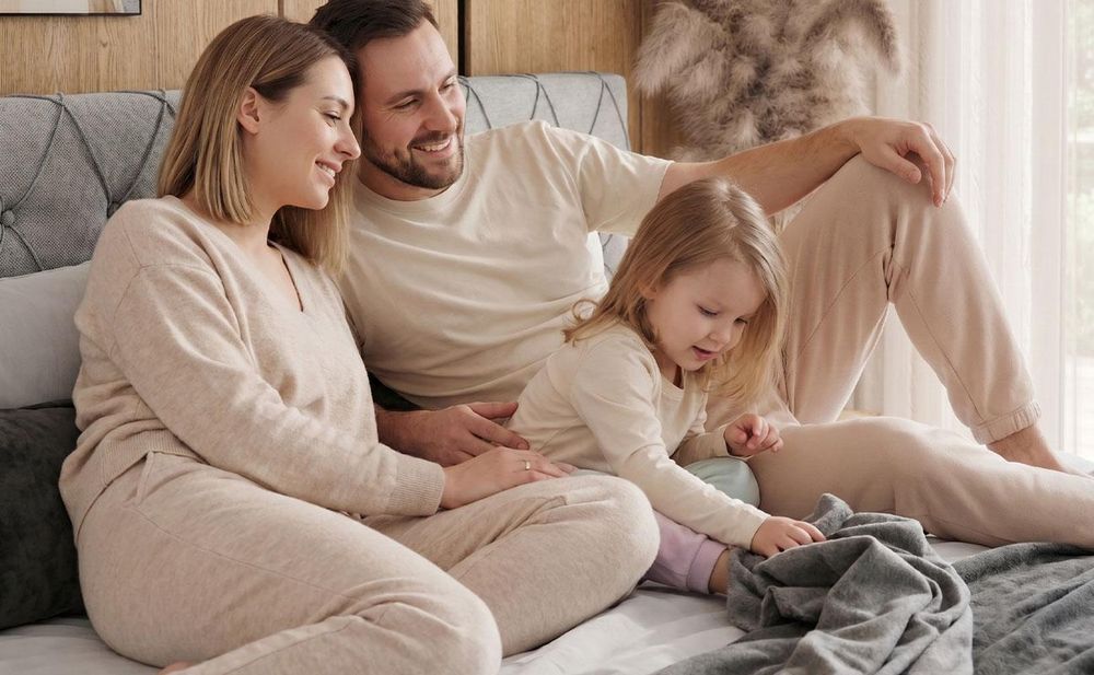 Gestepptes Kopfteil eines grau Bettes. Eine Topper-Matratze liegt auf dem Bett
