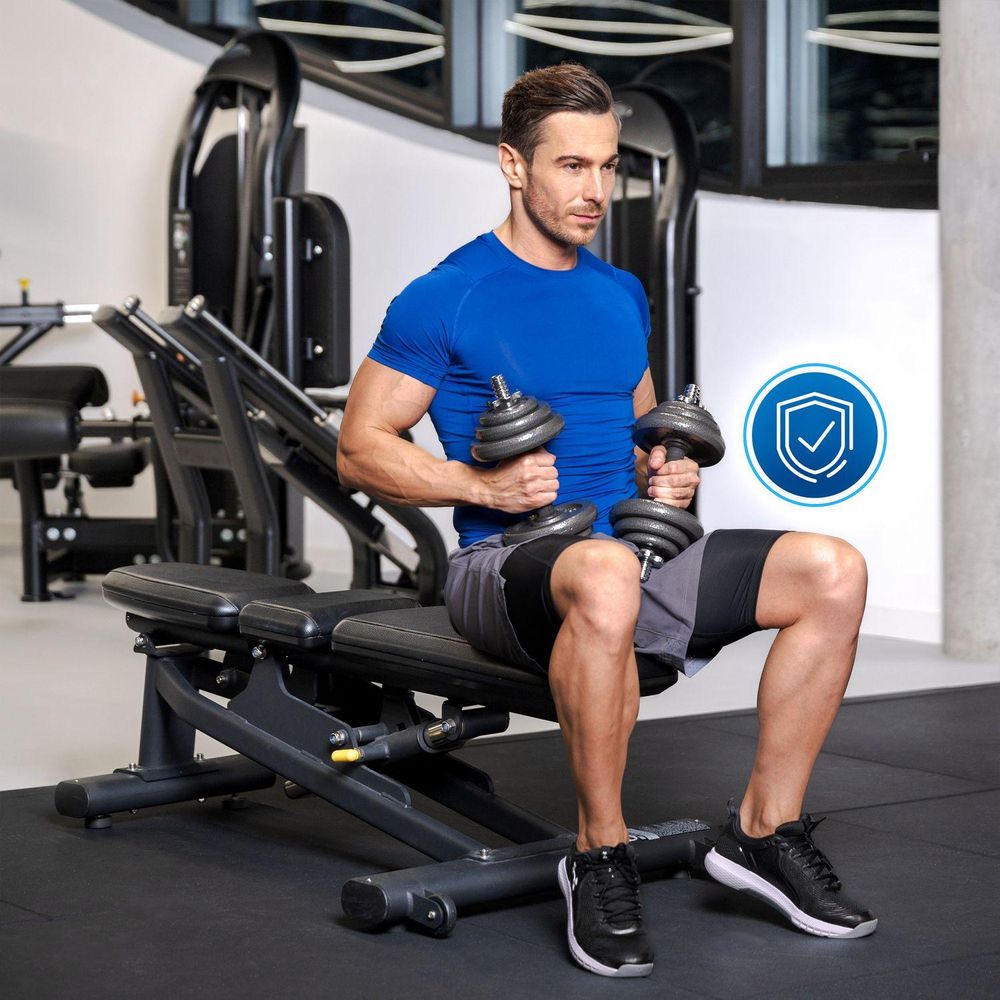 Mann trainiert Arme mit zwei Kurzhanteln im Fitnessstudio