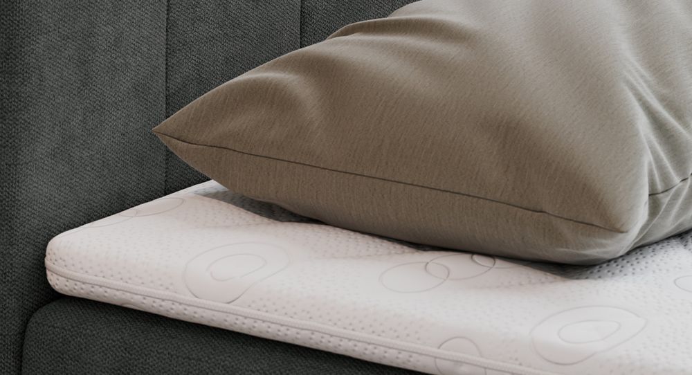 Gestepptes Kopfteil eines grau Bettes. Eine Topper-Matratze liegt auf dem Bett