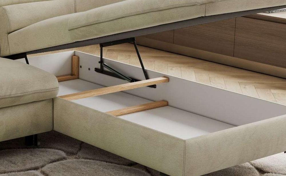 Detailansicht eines grauen Sofas mit Bettkasten und gepolsterter Sitzfläche.