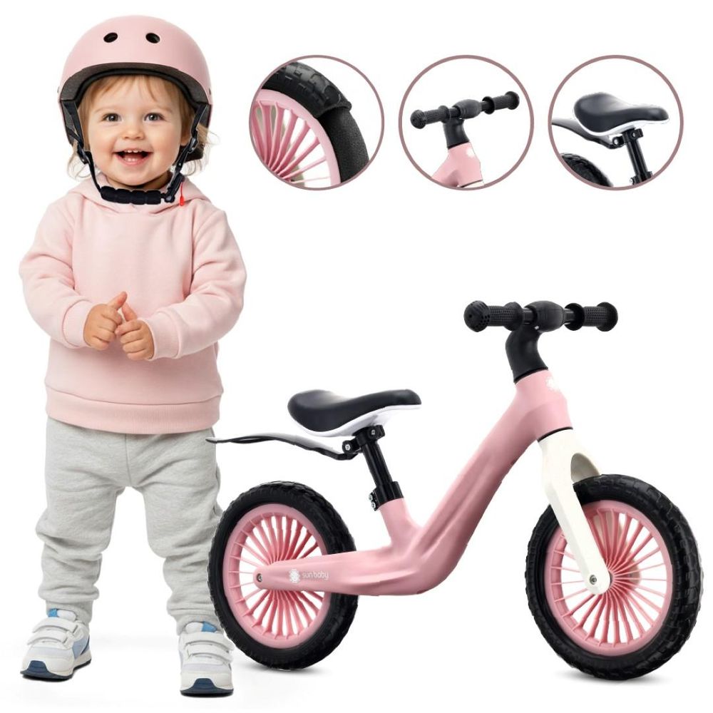 Niña pequeña junto a la bicicleta sin pedales Sun Baby Sport rosa, detalles de puños y asiento.