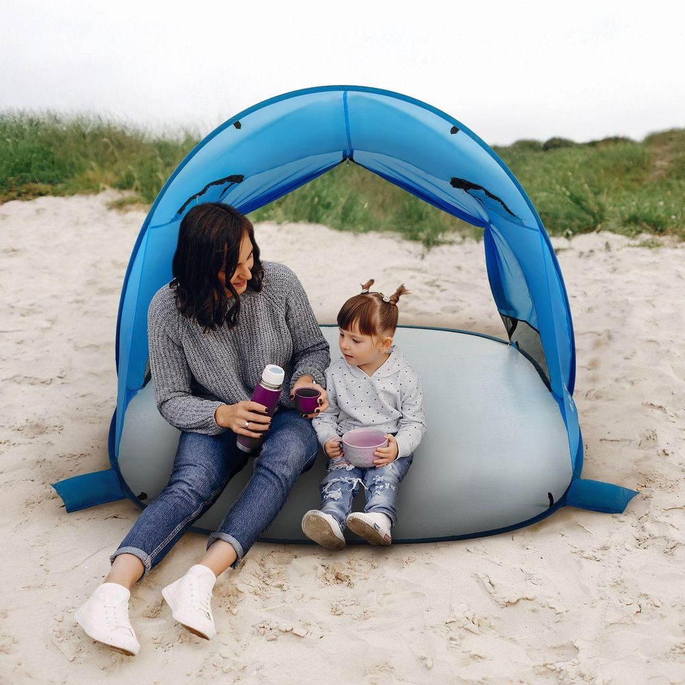 Mutter und Kind genießen Picknick im Strandzelt am Meer
