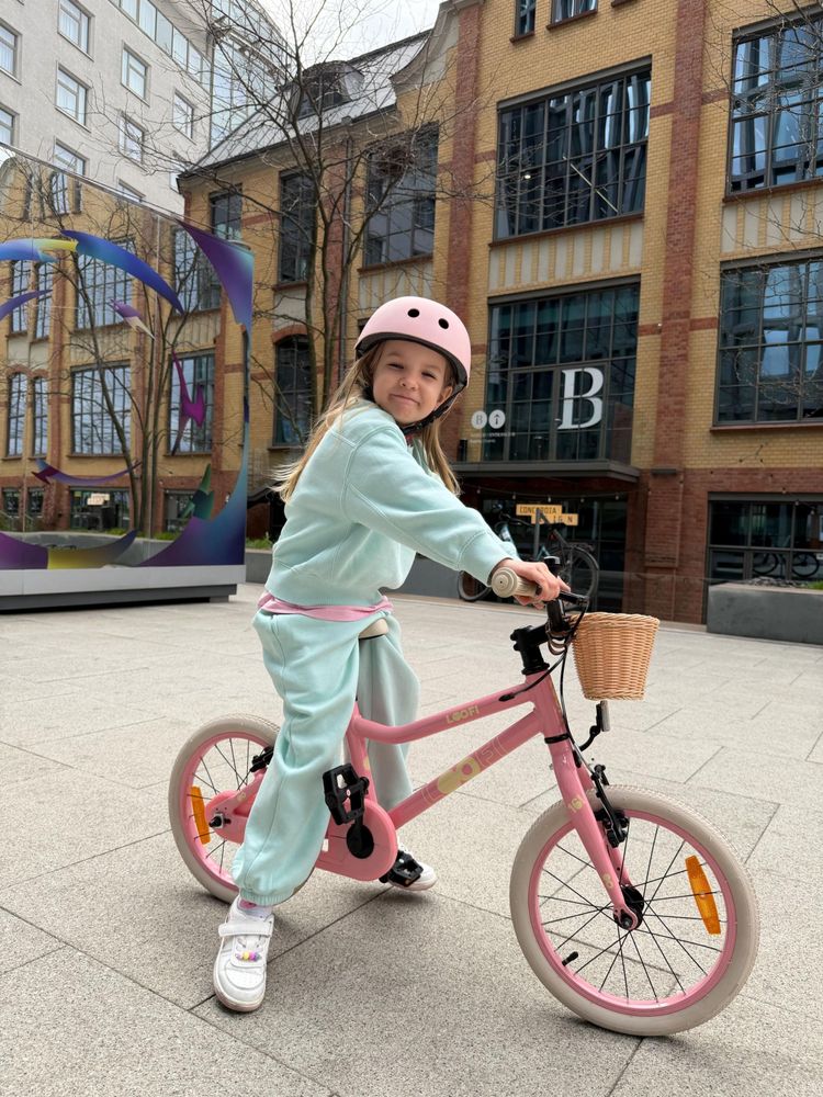 Kind fährt das pinke Fahrrad in der Stadt, trägt Helm